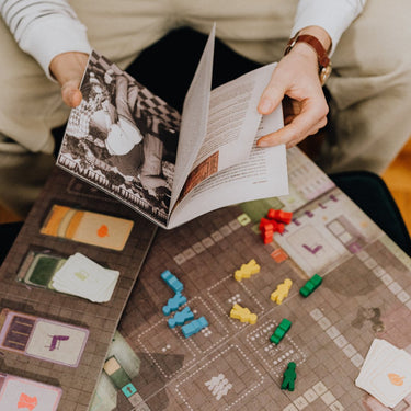 A person opening a booklet to a board game.